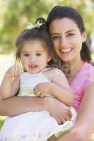 Mother holding daughter outdoors smiling