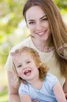 Mother holding daughter outdoors smiling