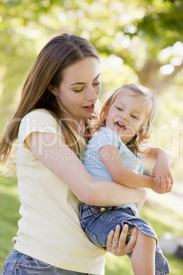 Mother holding daughter outdoors smiling