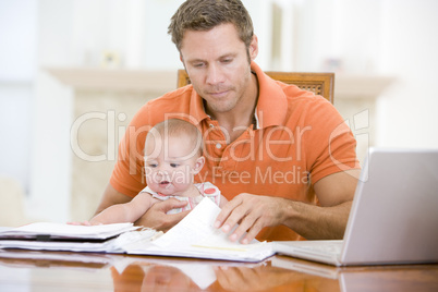 Father and baby in dining room with laptop