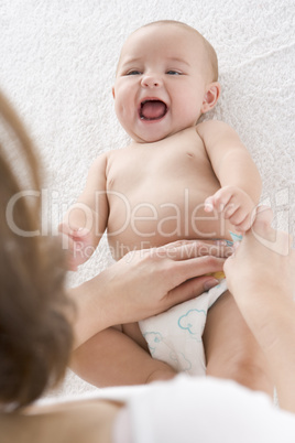 Mother changing baby's diaper indoors