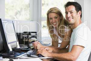 Couple in home office with computer smiling