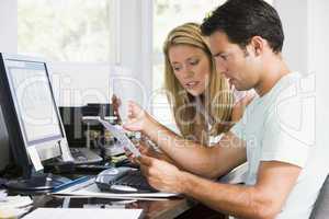 Couple in home office with computer and paperwork looking unhapp