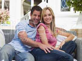 Couple sitting outdoors on patio smiling