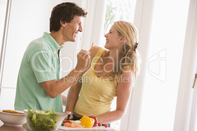 Couple in kitchen cutting up vegetables and smiling