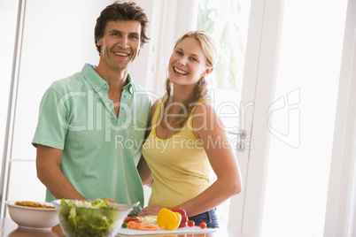 Couple in kitchen cutting up vegetables and smiling