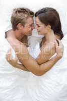 Couple lying in bed smiling