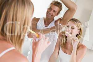 Couple in bathroom brushing teeth and applying deodorant