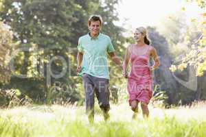 Couple running outdoors holding hands and smiling