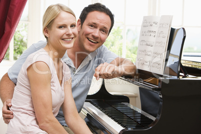 Couple sitting at piano smiling