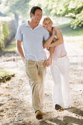 Couple walking outdoors arm in arm smiling