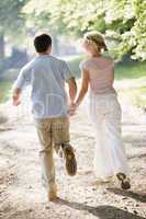 Couple running outdoors holding hands