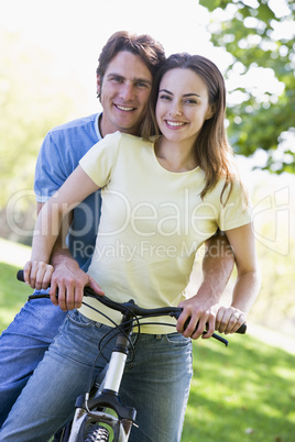 Couple on a bike outdoors smiling