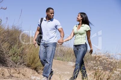 Couple walking on path holding hands and smiling