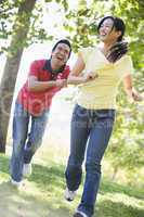 Couple running and being playful outdoors smiling