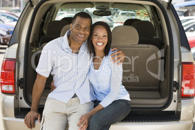 Couple sitting in back of van smiling