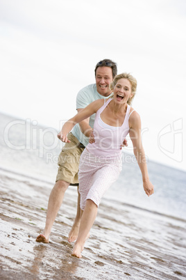 Couple running at the beach smiling