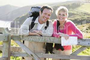 Couple on cliffside outdoors leaning on railing and smiling