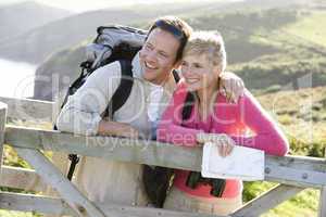 Couple on cliffside outdoors leaning on railing and smiling