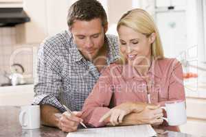 Couple in kitchen with newspaper and coffee smiling