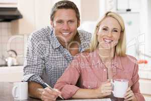 Couple in kitchen with newspaper and coffee smiling