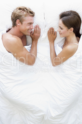 Couple lying in bed smiling