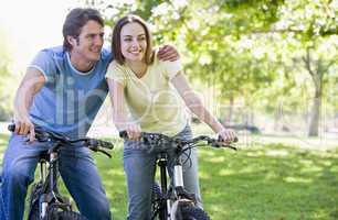 Couple on bikes outdoors smiling