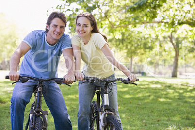 Couple on bikes outdoors smiling