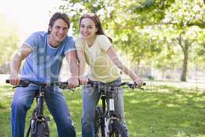 Couple on bikes outdoors smiling