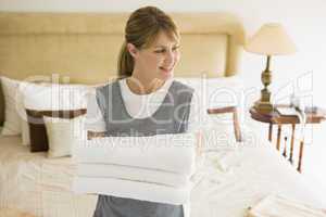 Maid holding towels in hotel room smiling