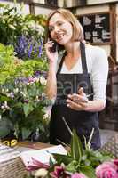 Woman working at flower shop using telephone and smiling