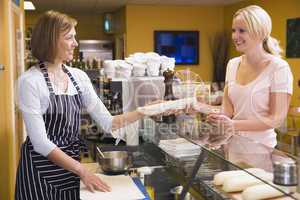 Woman standing at counter in restaurant serving customer and smi