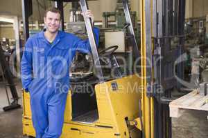 Warehouse worker standing by forklift