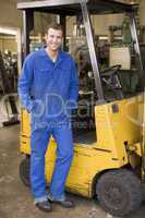 Warehouse worker standing by forklift