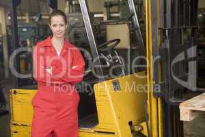 Warehouse worker standing by forklift