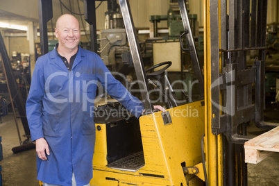 Warehouse worker standing by forklift
