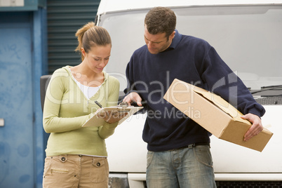Two delivery people standing with van holding clipboard and box