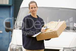 Delivery person standing with van with clipboard and box