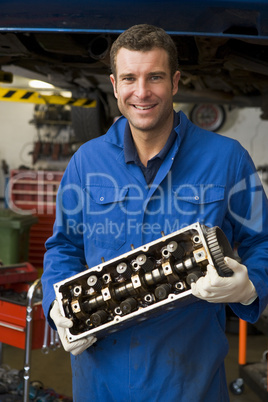 Mechanic holding car part smiling