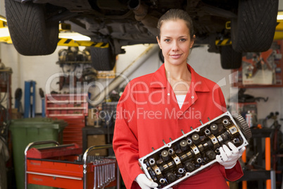 Mechanic holding car part smiling