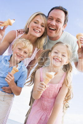 Family standing at beach with ice cream smiling