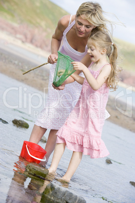 Mother and daughter at beach fishing and smiling