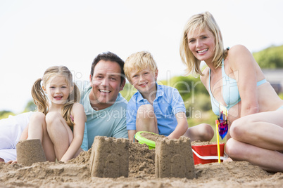 Family on beach making sand castles smiling