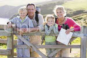Family on cliffside path leaning on fence and smiling
