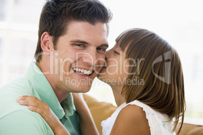 Young girl kissing smiling man in living room