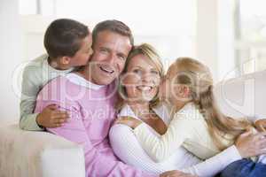 Family sitting in living room kissing and smiling