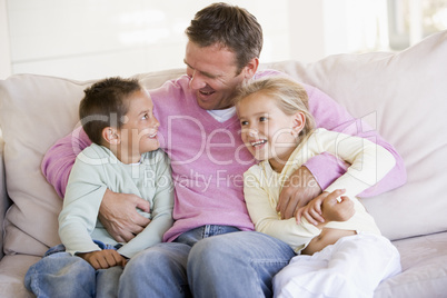 Man and two children sitting in living room smiling