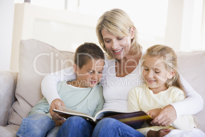 Woman and two children sitting in living room reading book and s