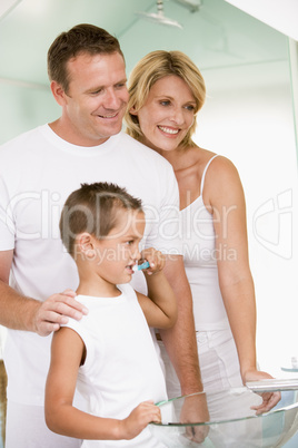 Couple in bathroom with young boy brushing teeth