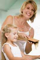 Woman in bathroom brushing young girl's hair